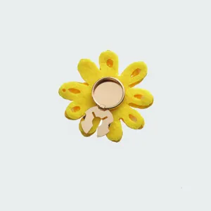 Vista dettagliata dell'accessorio floreale in feltro giallo, con la struttura della clip.