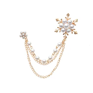 Detail view of the elegant gold-toned snowflake pearl chain brooch for suit decoration.
