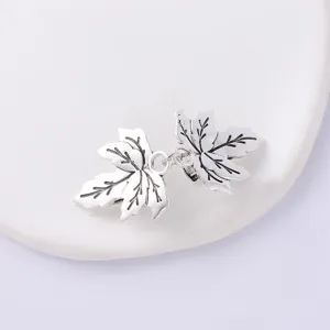 Close-up detail of silver maple leaf pattern scarf clip and clothing fastener accessory.