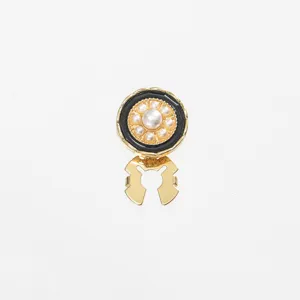 Detail shot of a delicate vintage pearl collar clip, featuring gold finish and black enamel.