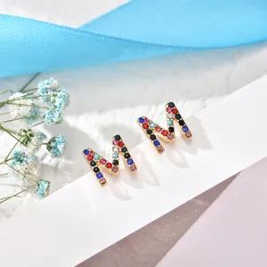Detail view of colorful rhinestone M letter stud earrings, exquisite metallic copper jewelry.