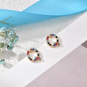 Close-up detail shot of colorful rhinestone letter Q stud earrings, delicate copper jewelry.