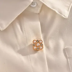 Close-up detail of a pearl and rhinestone decorative shirt button, elegant collar accessory.