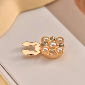 Detailed close-up of a luxury gold-tone pearl and crystal decorative shirt button.