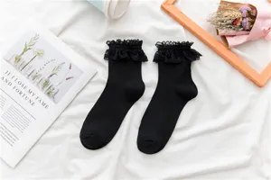 Dettaglio di un paio di calzini al polpaccio in pizzo nero con balze, stile Lolita JK.