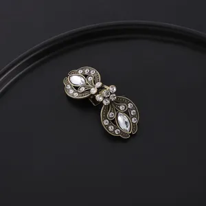 Vintage rhinestones filigree scarf clip detail shot, elegant antique brass metal collar brooch.