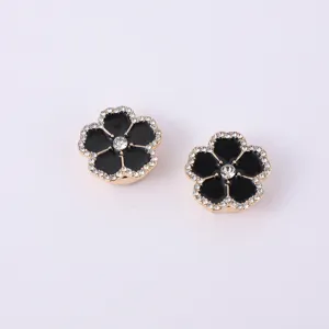 Gros plan détail de luxe des boutons de manchette en métal fleur strass émail noir.