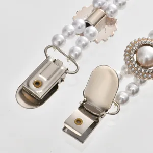 Detailed close-up view of elegant pearl rhinestone sweater clips with fine metal duckbill clasps.