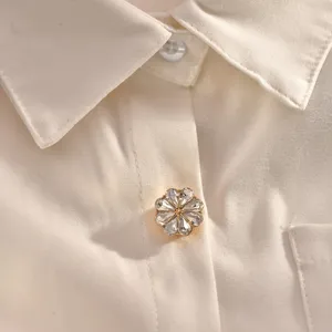 White shirt detail featuring a delicate sparkling floral rhinestone button collar accessory.