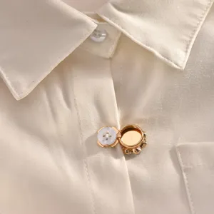 Close-up detail view of white shirt collar featuring elegant gold decorative button.