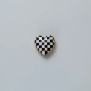 Black and white checkerboard heart detail shot of stylish cufflink and shirt accessory.