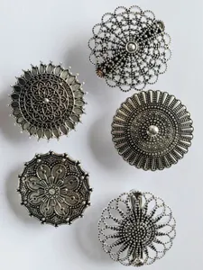 Close-up details of vintage hollow metal shawl clips and scarf buckles in ethnic floral style.