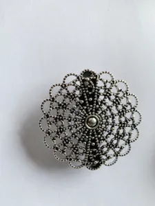 Detailed shot of vintage silver filigree round floral shawl clip scarf buckle accessory.