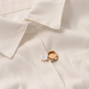 Gedetailleerde close-up van een delicate goudkleurige overhemd-sierknop en clip.