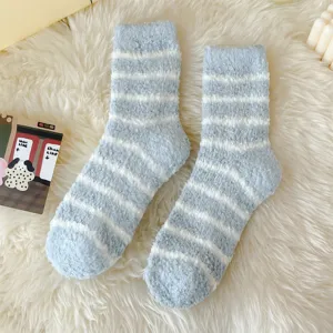 Close-up detail of cozy fuzzy striped coral fleece socks in light blue and white for home wear.