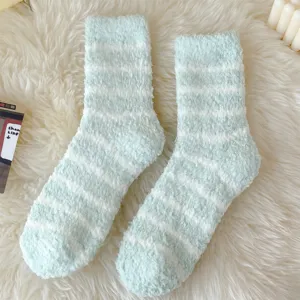 Detailed shot of cozy mint green and white striped fluffy fuzzy socks on a soft white rug.