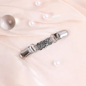 Exquise retro snijwerk metalen trui clip detail, toont een delicaat bloemenpatroon.