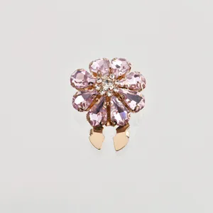 Primo piano sul dettaglio della spilla a fiore con strass rosa e cristalli scintillanti.
