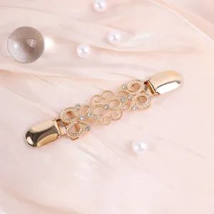 Gedetailleerd overzicht van vintage gouden filigrein trui-clip met strass inleg.