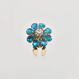Dettaglio bottone floreale in cristallo blu e strass per camicie eleganti e foulard.