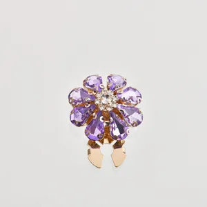 Primo piano dettagliato di un bottone floreale in cristallo viola con scintillanti strass oro.