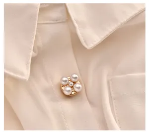 Detailaufnahme einer eleganten weißen Damenbluse mit hochwertigem Perlen-Zierknopf.