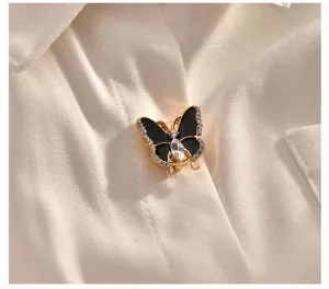 Close-up of a rhinestone butterfly shirt brooch, delicate metal and enamel details.