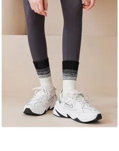Close-up detail shot of breathable gradient mid-tube yoga socks worn with athletic sneakers.