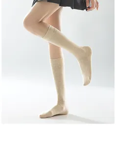 Dettaglio di calze al polpaccio beige da donna, trama a maglia morbida e comoda vestibilità.