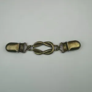 Close-up van vintage bronzen trui clip met knoopontwerp en fijne metalen textuur.