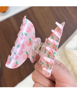 Détail en gros plan de jolie pince à cheveux motif pêche rose, en acrylique transparent.