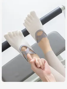 Close-up detail of white five-toe yoga socks with grey cross straps on pilates equipment
