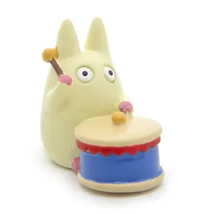 Detailed close-up shot of the cute white anime figurine playing a drum, resin decorative ornament.