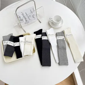 Vue détaillée de chaussettes longues côtelées unies en noir et blanc sur la table.