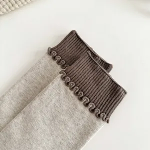 Detail shot of cotton knit mid-tube socks with fine vertical stripes and contrast ruffle cuff.
