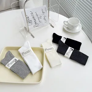 Vue détaillée de chaussettes longues en coton uni en noir, blanc, gris et beige.