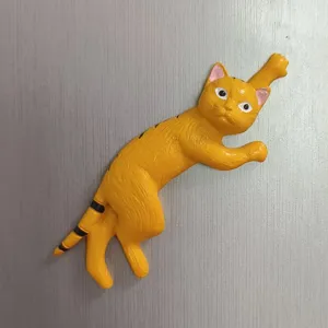 Nahaufnahme Detail eines süßen orangefarbenen Katzen Kühlschrankmagneten im kreativen Kletterdesign.