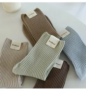 Detail view of women ribbed mid-calf socks in soft macaron colors with cute paper tags.