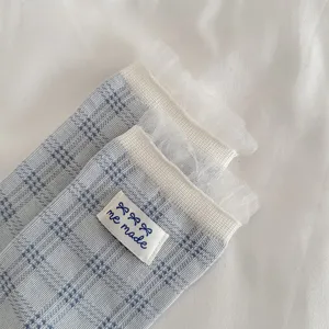 Detail view of blue plaid women socks with white mesh ruffle trim and me made label design.