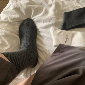 Vista dettagliata di calzini grigio scuro a coste verticali su un letto bianco accogliente.