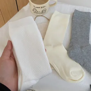 Vista dettagliata di calze a costine da donna a metà polpaccio in bianco, beige e grigio.