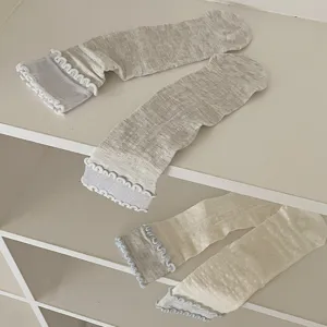 Detail view of ruffled lettuce edge mid-calf socks with vertical striped knit texture.