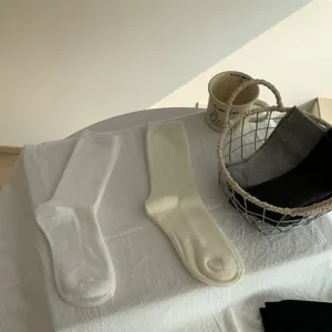 Vista dettagliata di calze a costine morbide e accoglienti in toni neutri disposte su un tavolo.