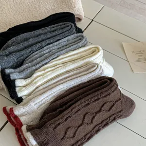 Knit slouch socks detailed with cable texture and contrast cuffs, perfect for cozy winter wear.