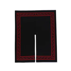 Nahaufnahme des ethnischen schwarzen Umhangs mit roten traditionellen Mustern und Details.