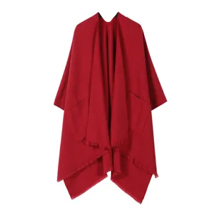 Detailansicht des eleganten roten Cape mit praktischen Vordertaschen und schöner Fransenborte.