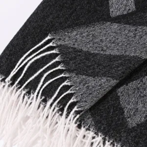 Detailed close-up view of black and grey plaid winter tassel shawl soft fabric texture.