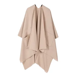 Detailansicht des lässigen offenen, beigen Capes mit Vordertaschen und Fransenborte.