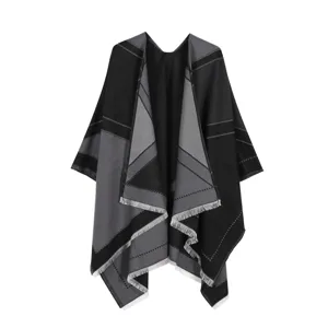 Detailed view of black and gray geometric patterned knit cape shawl with elegant fringe accent.