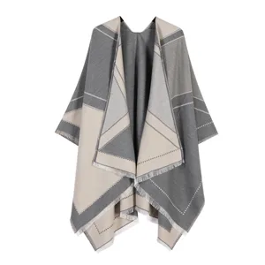 Close-up detail of the stylish grey and beige colorblock poncho cape featuring elegant fringe edges.